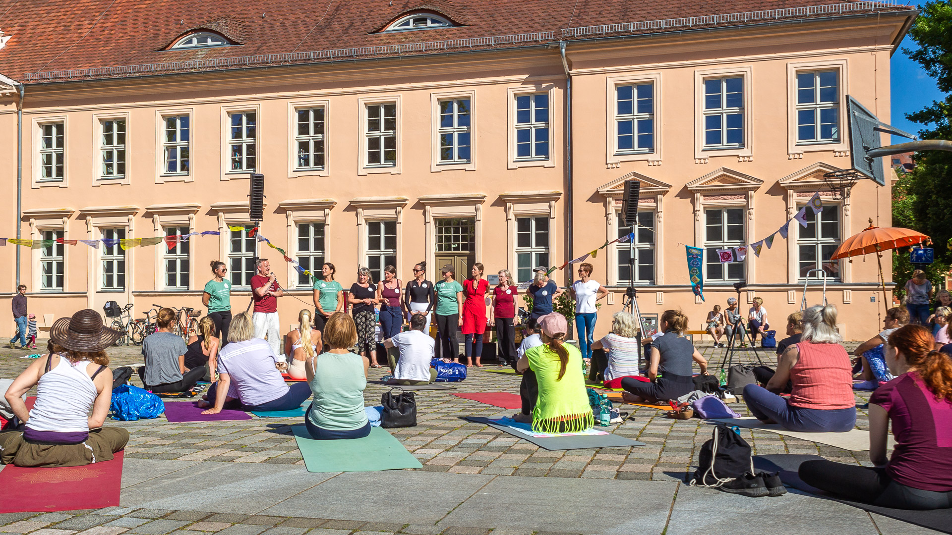 Vor dem alten Gymnasium haben zahlreiche Teilnehmer und Teilnehmerinnen ihre Yogamatten ausgebreitet